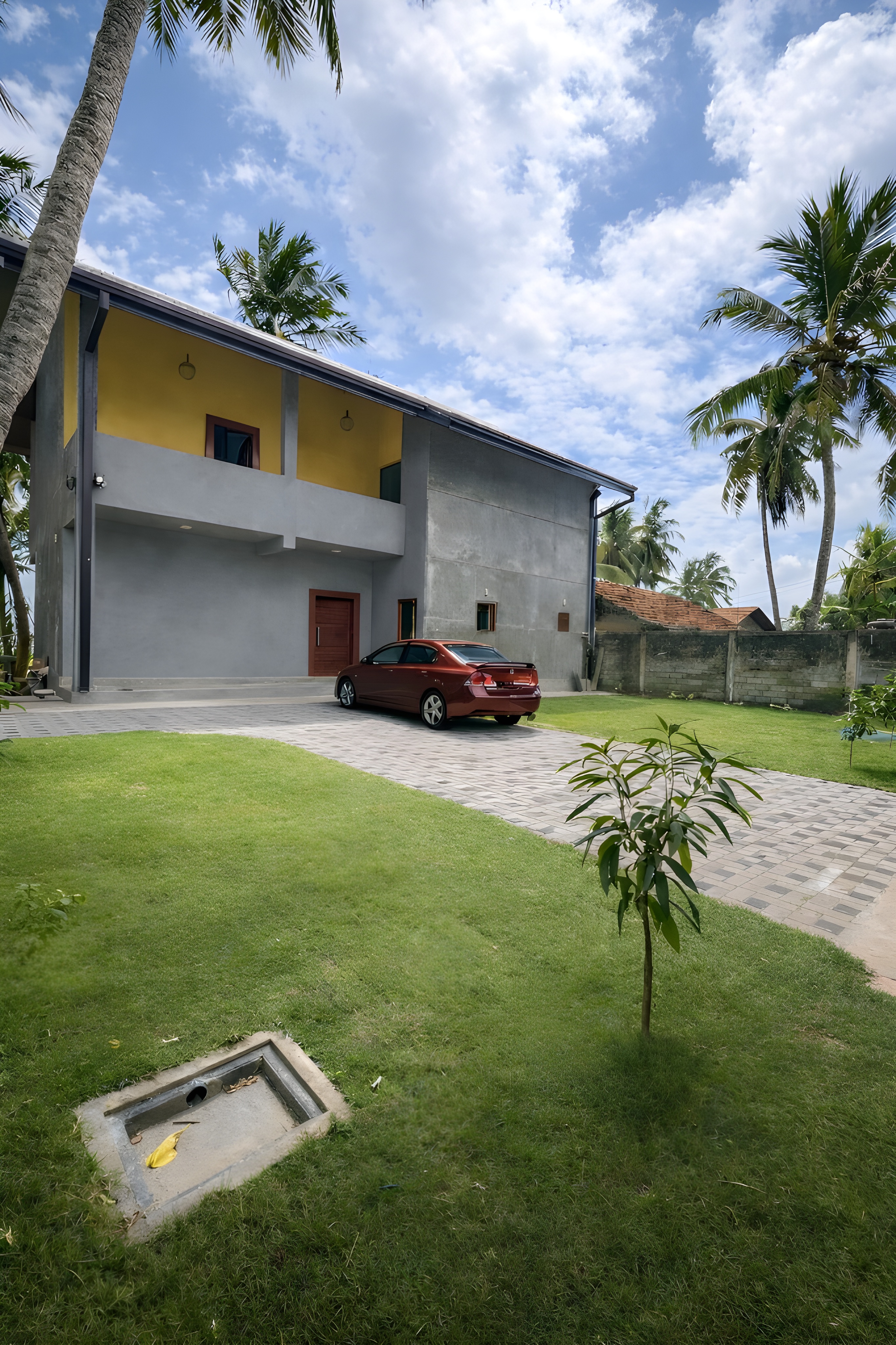 CocoBaru villa exterior with garden, driveway and palm trees